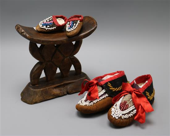 A pair of beaded North American Indian childs moccasins, a similar miniature pair and a tribal carved head rest